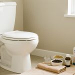 Salle de bain propre avec un verre d’eau, des aliments riches en fibres, une serviette chaude et une trousse de soins évoquant un soulagement sûr de la constipation.